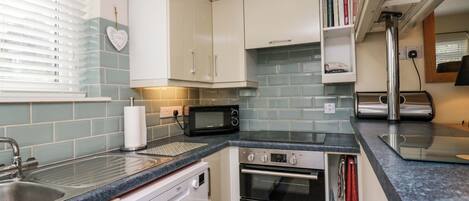 A compact kitchen with white cabinets, a microwave, an oven, and a dishwasher.
