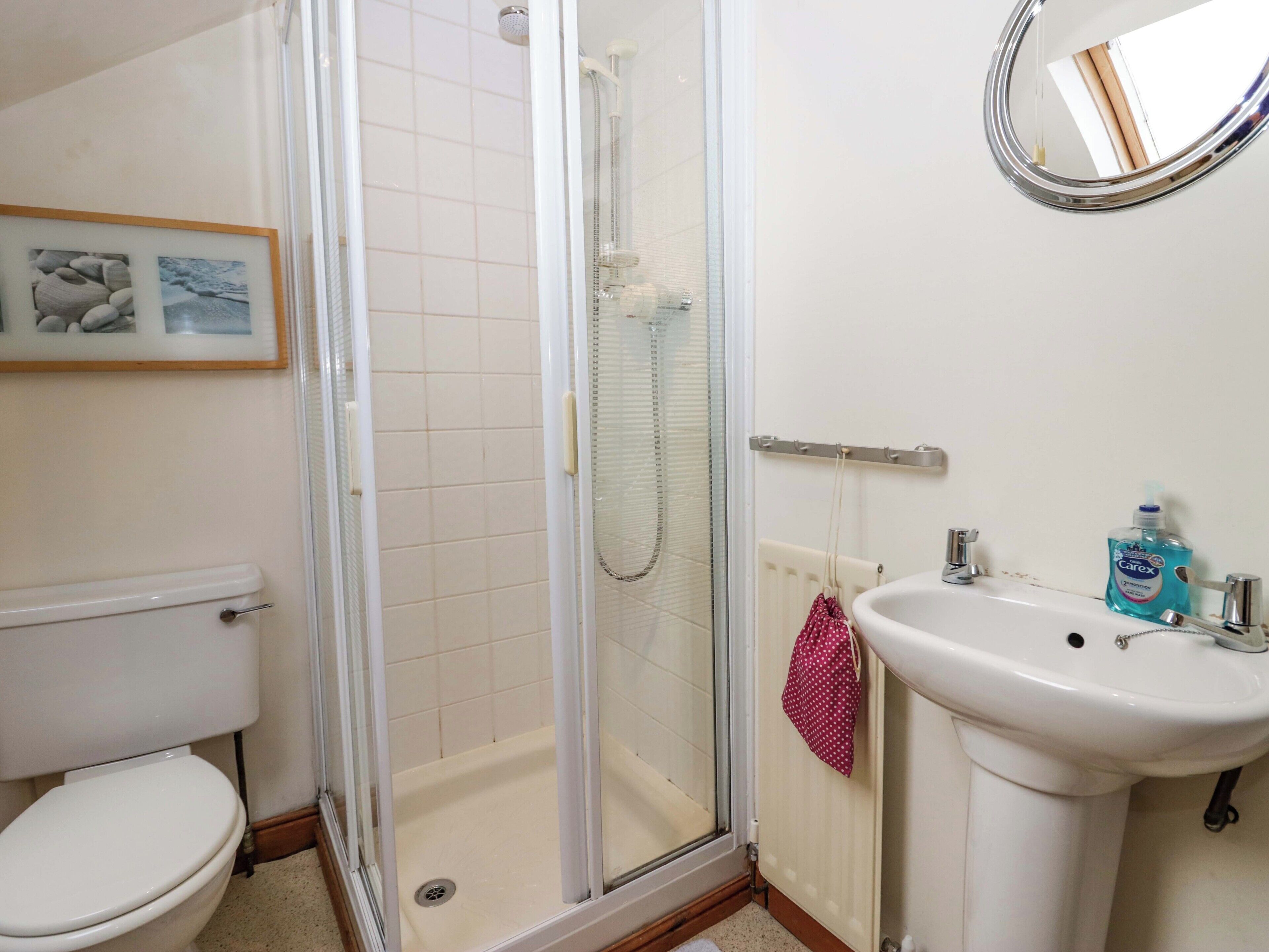 Un baño con inodoro, ducha de vidrio, lavabo y espejo.