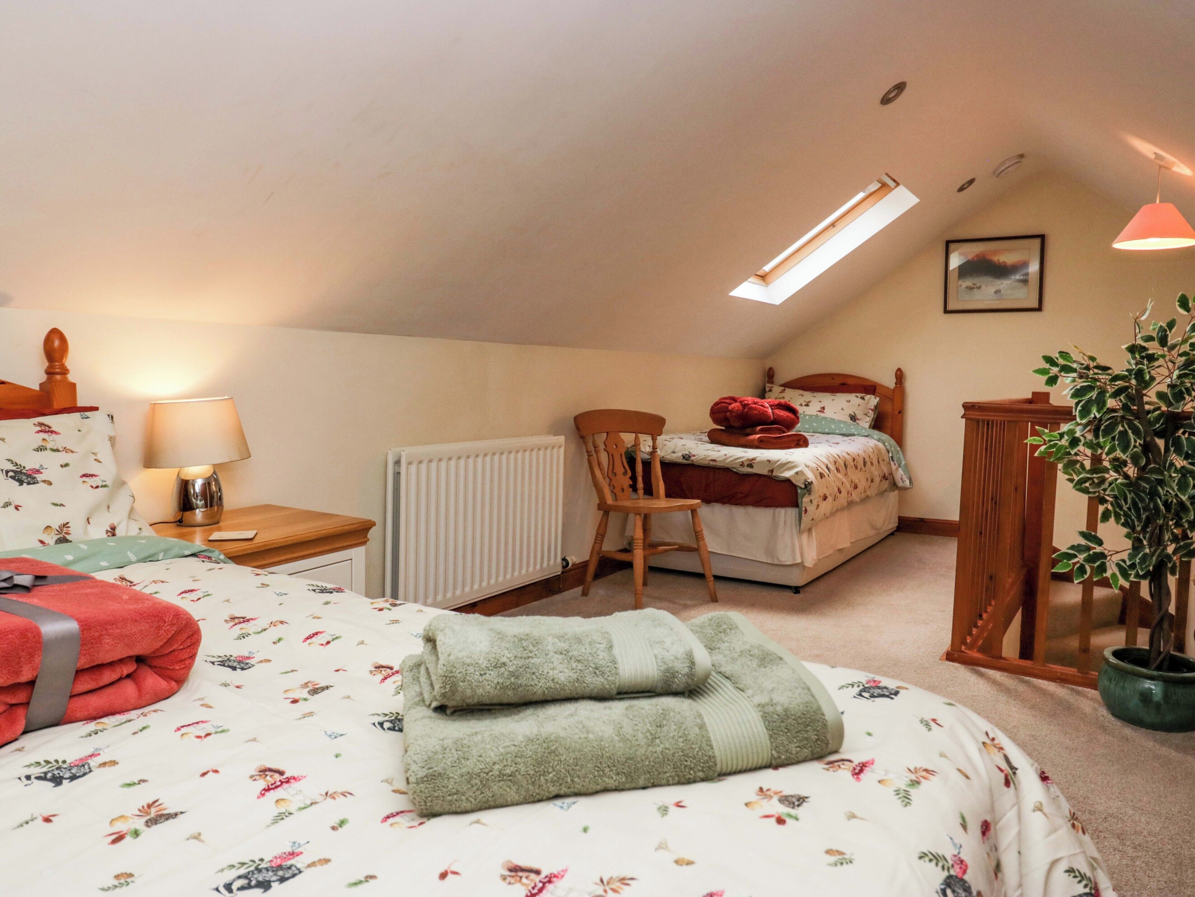 A bedroom with a bed, a chair, a desk, a radiator, a lamp, a plant, and a picture on the wall.