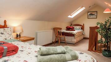A bedroom with a bed, a chair, a desk, a radiator, a lamp, a plant, and a picture on the wall.