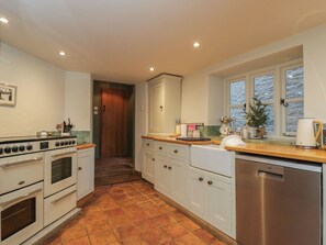 A kitchen with a double oven, a dishwasher, and a window with a view. - Meadow View Cottage (Cheltenham)
