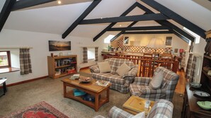 Ein gemütliches Wohnzimmer mit hohen Decken, Kamin, Essbereich und Küche.