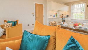 A modern living room with a sofa set and a dining table with a glass partition. - 4 The Manor House Hillfield Village (Dartmouth)