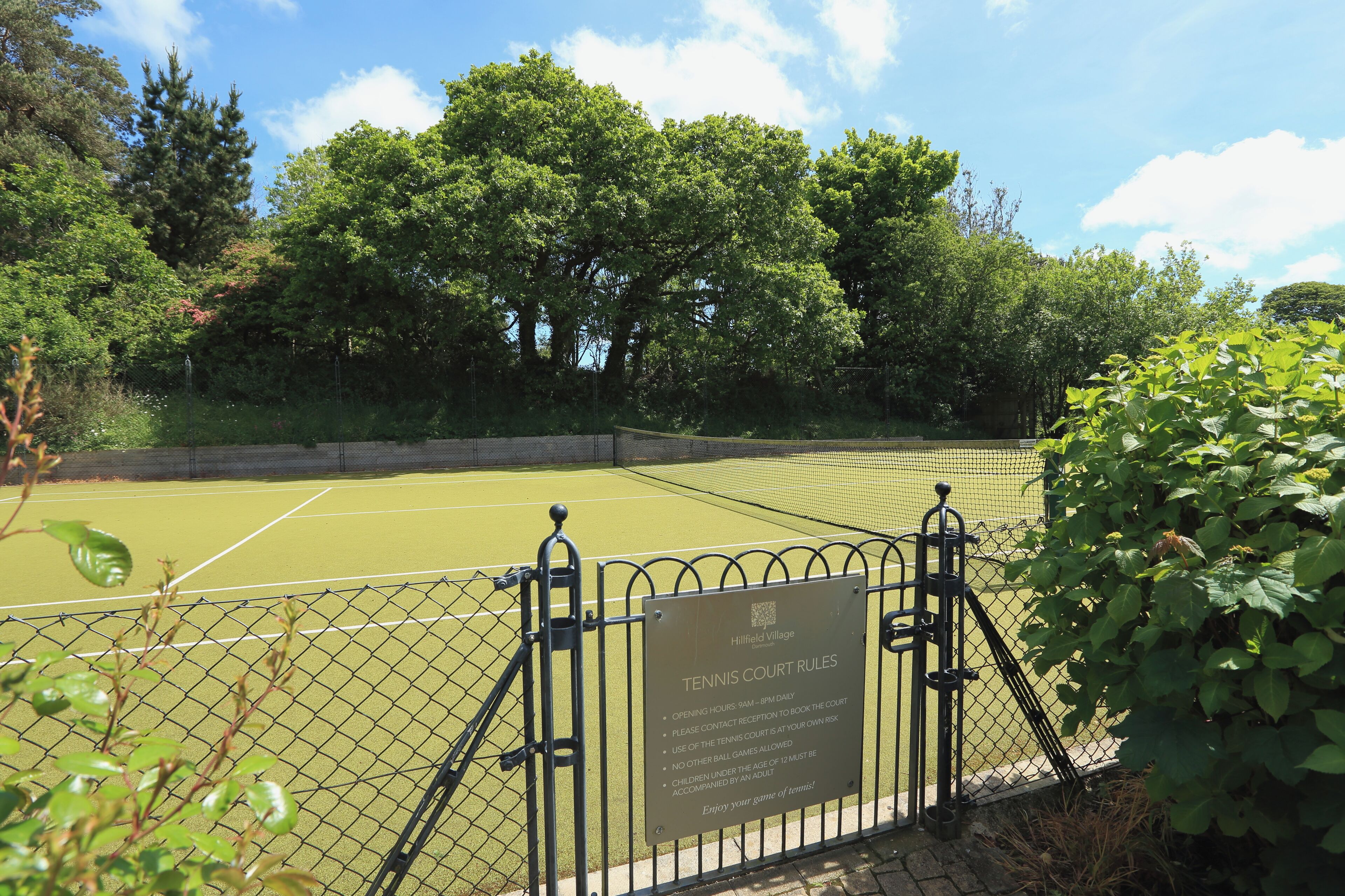 Ein Tennisplatz mit einem Schild, das die Platzregeln erklärt.