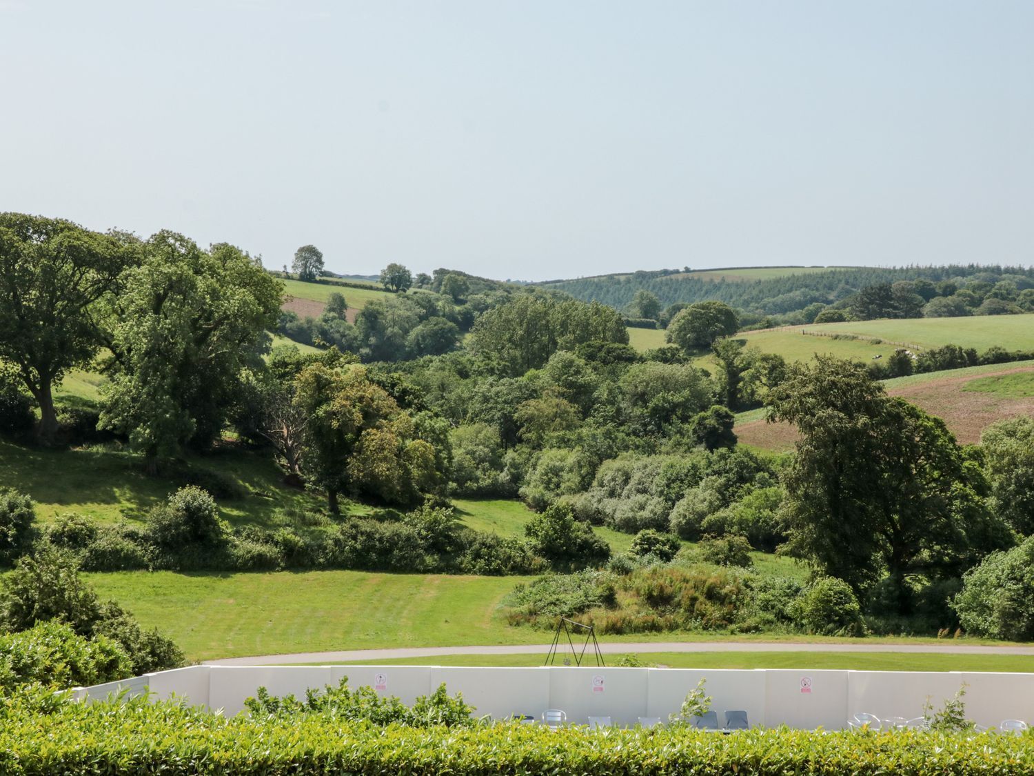 A rural landscape with rolling hills, dense greenery, and a clear sky.