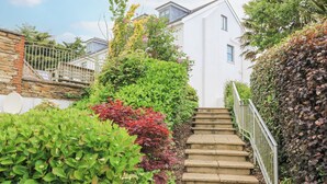 A staircase leading to a white building surrounded by lush greenery and a stone wall. - 4 The Manor House Hillfield Village (Dartmouth)