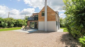 A modern house with a sloped roof, a visible chimney, and a gravel driveway.