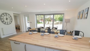 A modern kitchen with a wooden countertop, white cabinets, and a dining area with chairs and a table set for four.