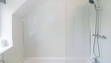 Un baño moderno con cabina de ducha de vidrio, bañera y retrete.