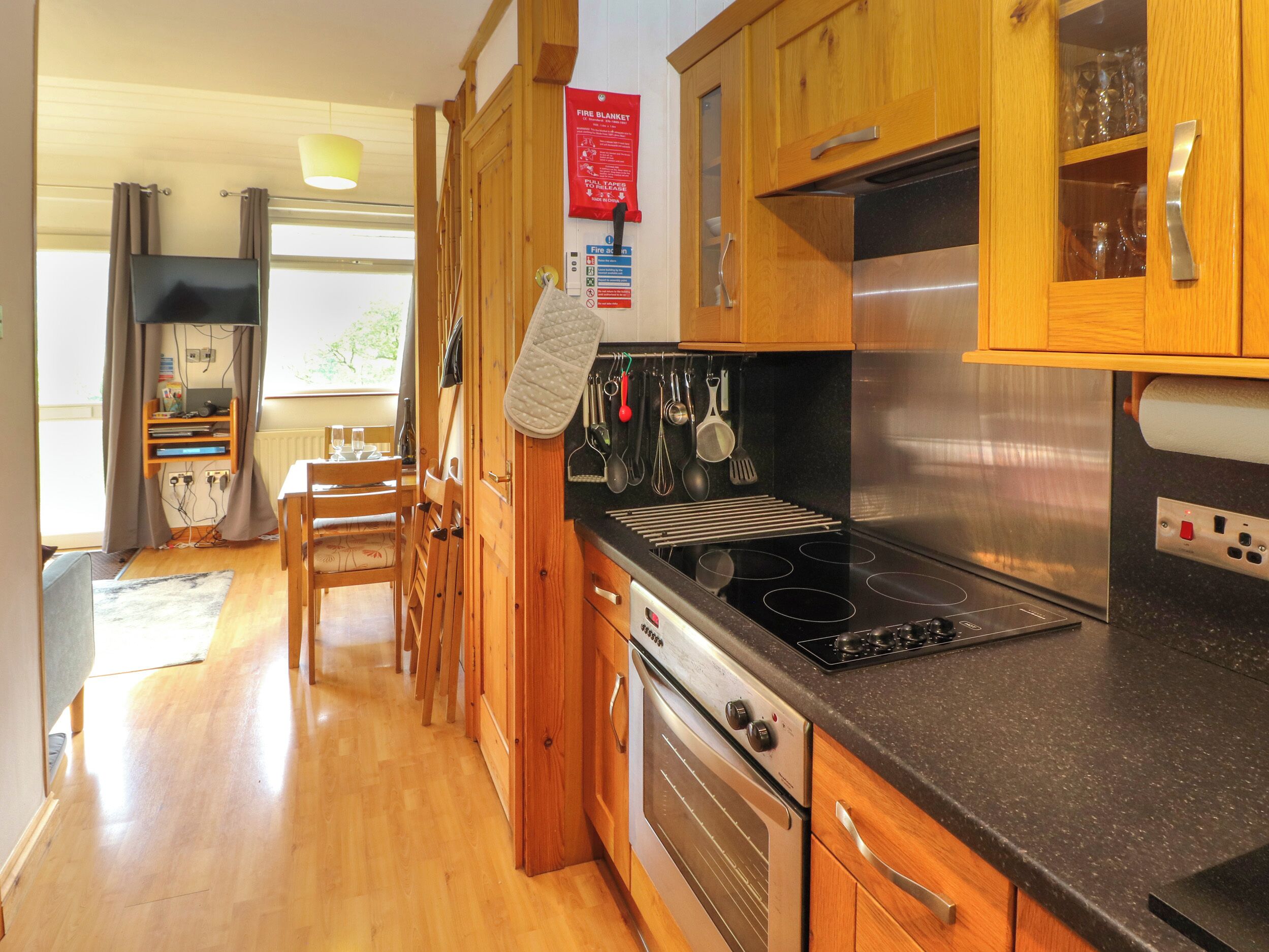 A kitchen with wooden cabinets, a stainless steel stove, and a dining area with a table and chairs.