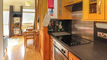 A kitchen with wooden cabinets, a stainless steel stove, and a dining area with a table and chairs.