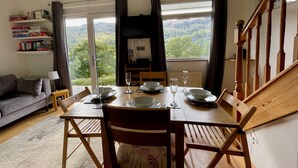 A dining area with a table set for four, a sofa, and a bookshelf.