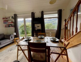 Un comedor con una mesa dispuesta para cuatro personas, un sofá y una estantería.