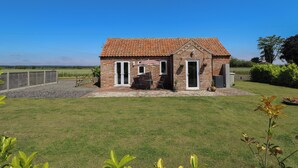 A small brick house with a tiled roof, a front door, and a patio area with a table and chairs. - The Stable (Boston)