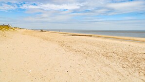 A wide sandy beach with a clear sky and a few clouds. - Flint Cottage (Great Yarmouth)