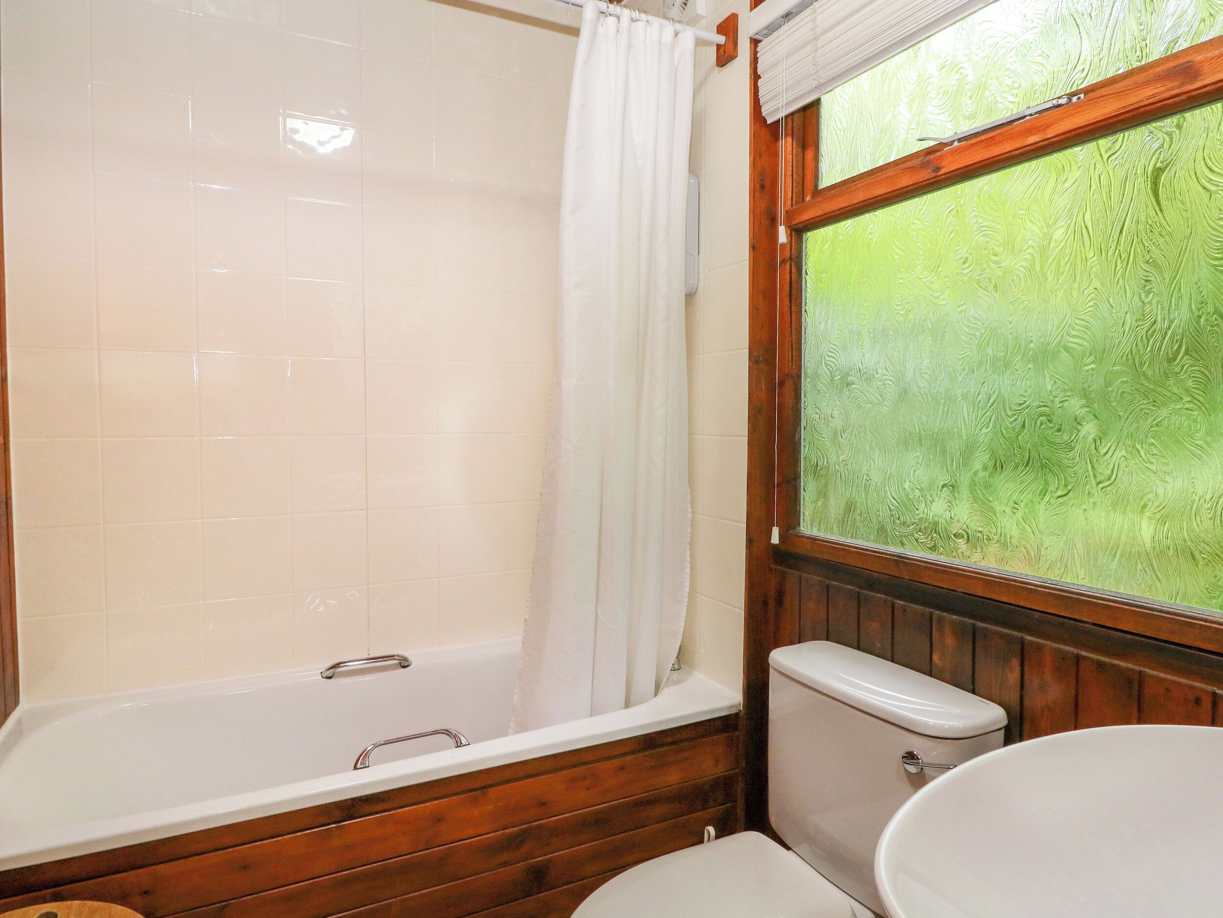 A bathroom with a wooden bathtub, a toilet, and a sink.