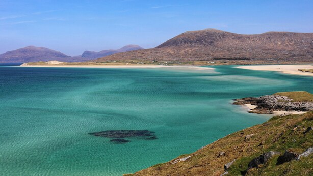 A coastal landscape with clear turquoise waters, sandy beaches, and distant mountains. - Riverside (Harris)