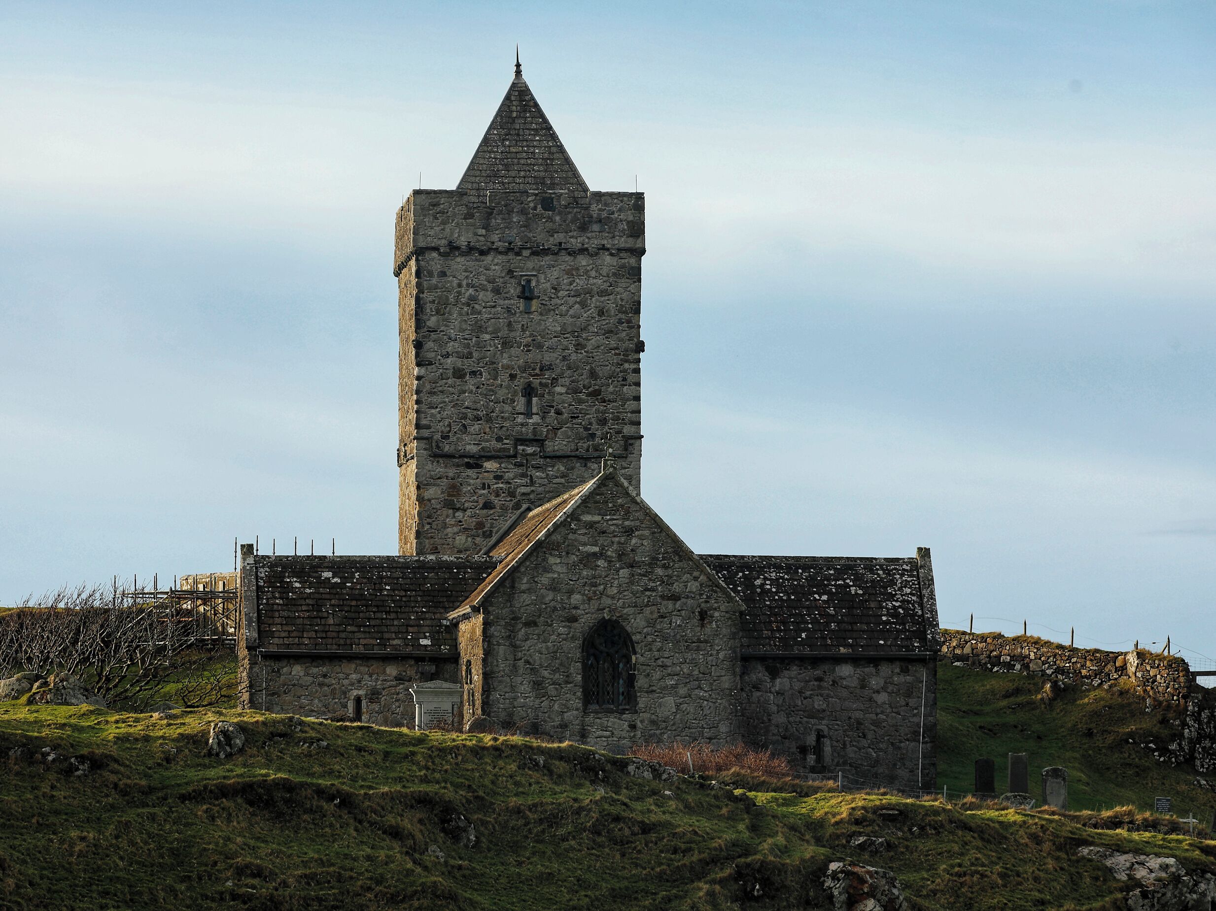 A stone church with a tall tower and a small entrance.