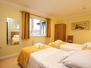 A hotel room with two beds, a wardrobe, a mirror, a window with curtains, and a painting on the wall.