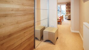 A hallway with a wooden wall, a glass partition, and a view into a living area with a sofa and curtains. - Riverside (Harris)
