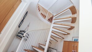 A spiral staircase with wooden steps and white railings, leading to an upper floor. - Azur (St Ives)