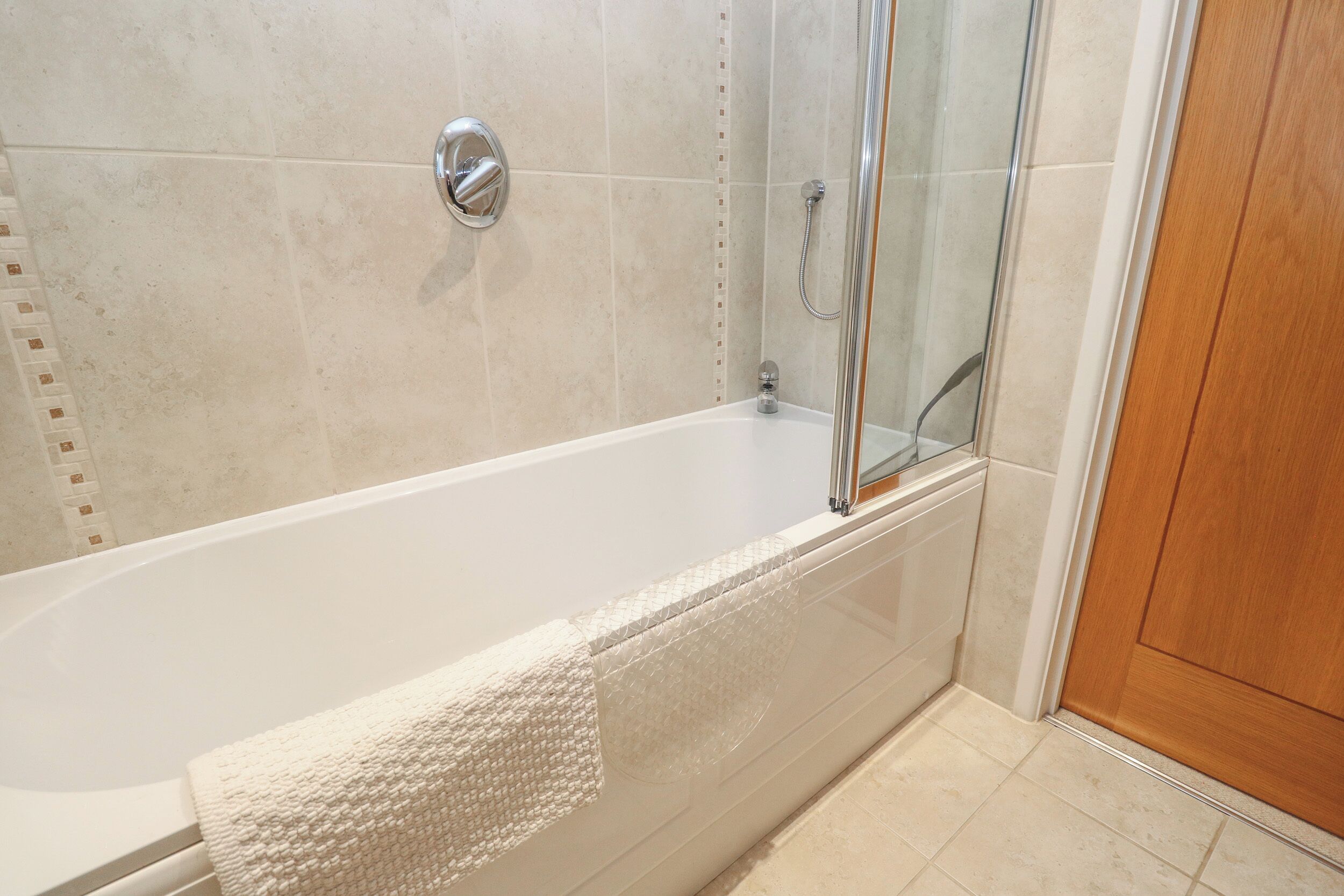 Une salle de bain moderne avec une baignoire, une douche et une porte en bois.