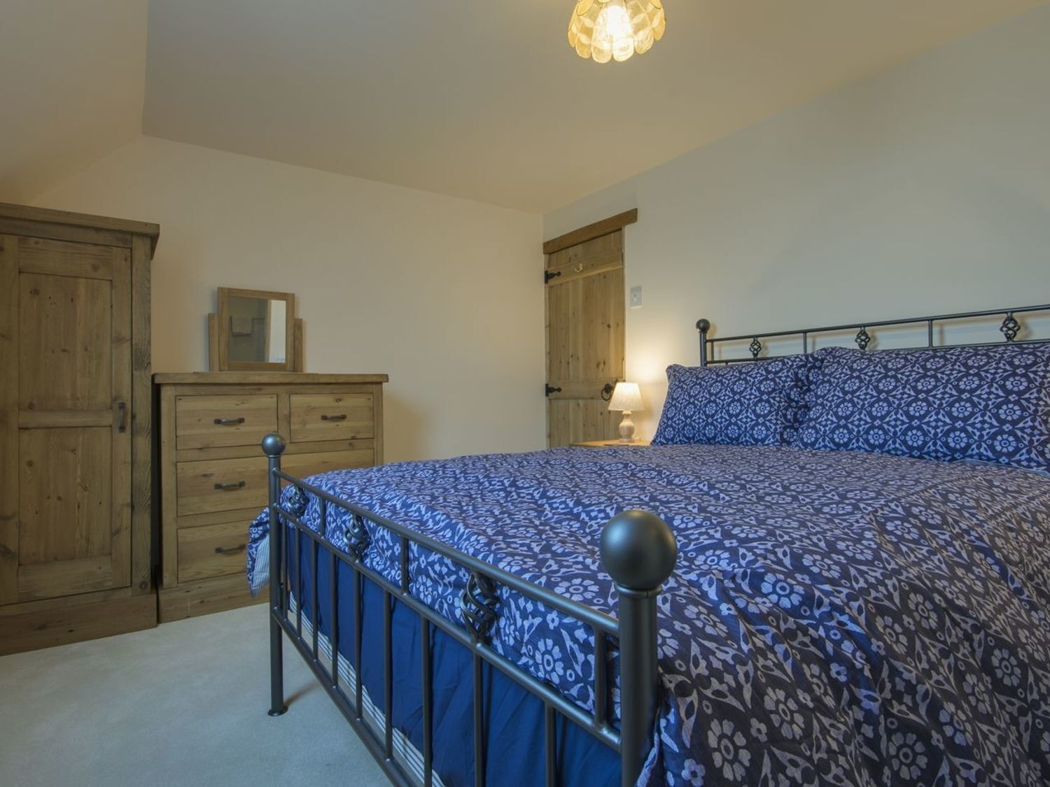 Une chambre à coucher avec un lit, une armoire en bois et une table de chevet avec une lampe.