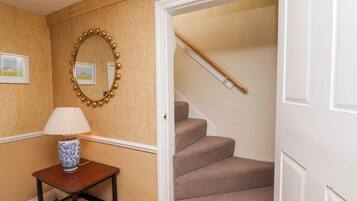 A hallway with a lamp, a mirror, and a staircase.