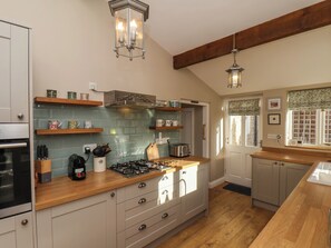 A kitchen with a gas stove, wooden countertops, and a backsplash.