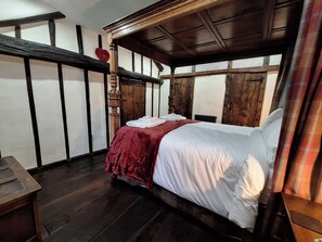 A traditional room with a four-poster bed, wooden walls, and a red bedspread. - Field House (Keswick)