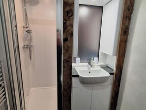 A bathroom with a shower, a sink, and a mirror. - Field House (Keswick)