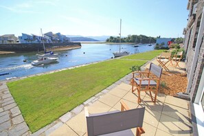 A patio with outdoor furniture overlooking a canal with boats. - Harbour Escape (Porthmadog)