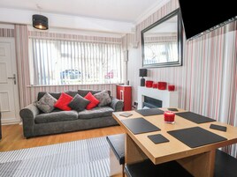 Uma sala de estar com sofá, mesa de jantar, lareira e cortinas listradas.