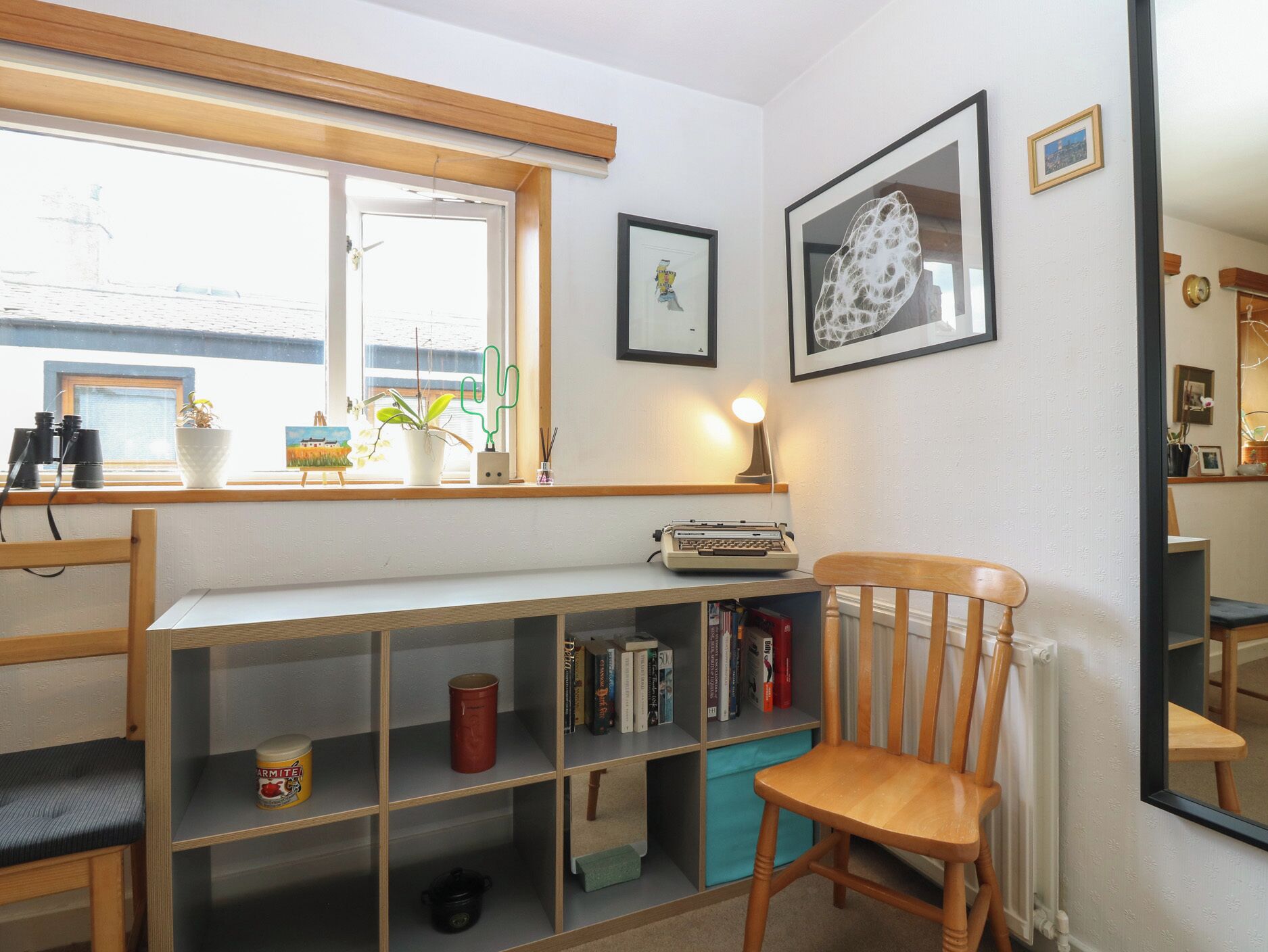 A room with a desk, chair, bookshelf, window, and radiator.