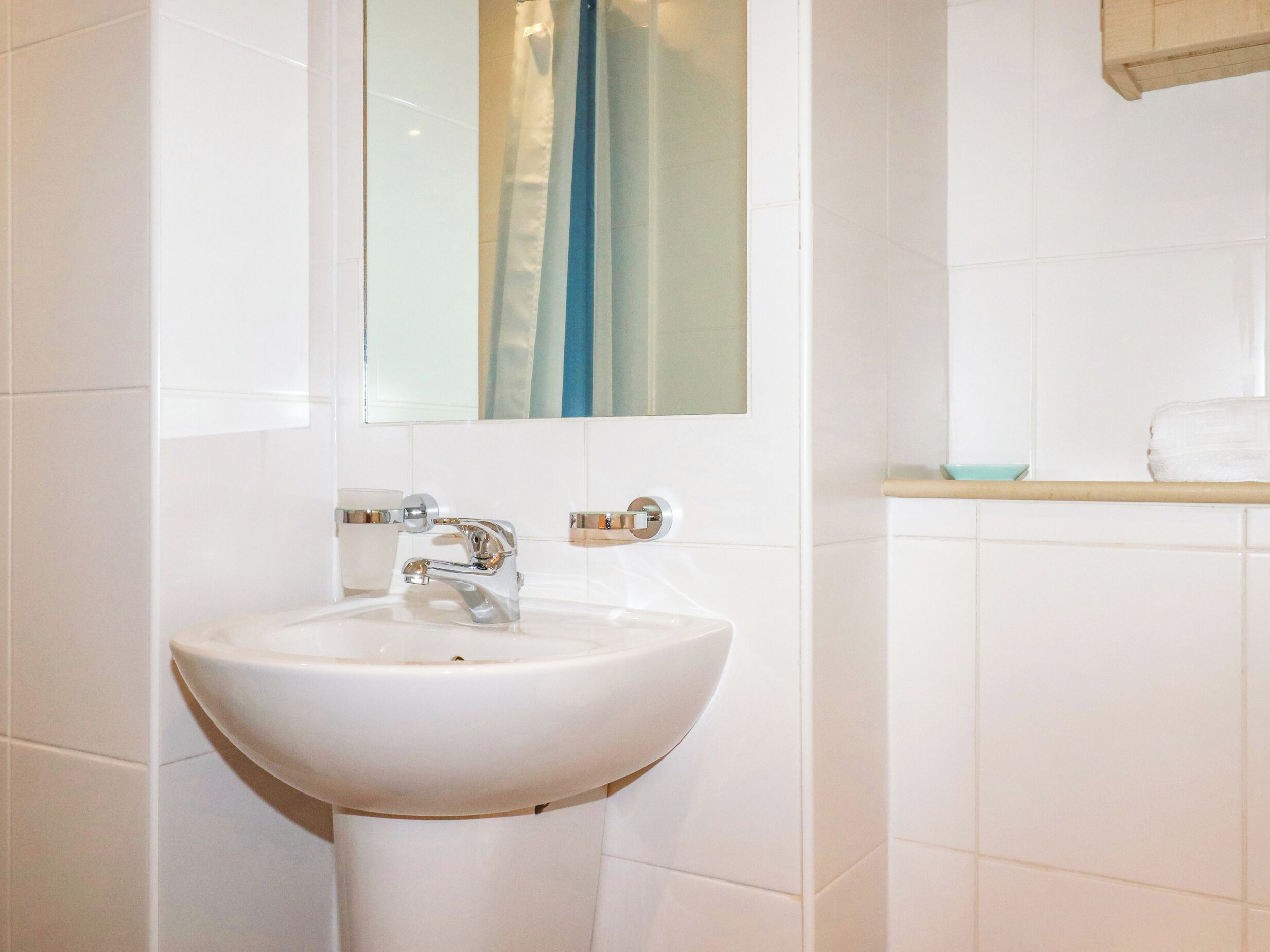 A bathroom with a white sink, chrome faucet, and a mirror above it.