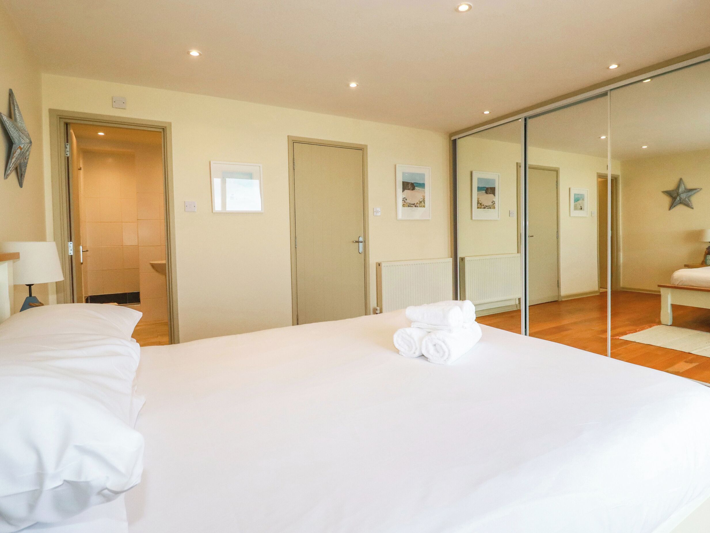 A hotel room with a large bed, a mirror, and a view of the beach through the window.