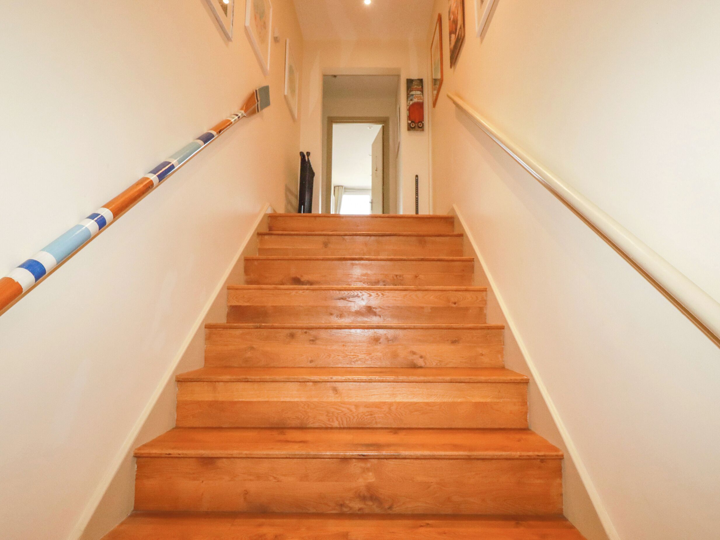 A wooden staircase with handrails on both sides, leading to an open doorway.