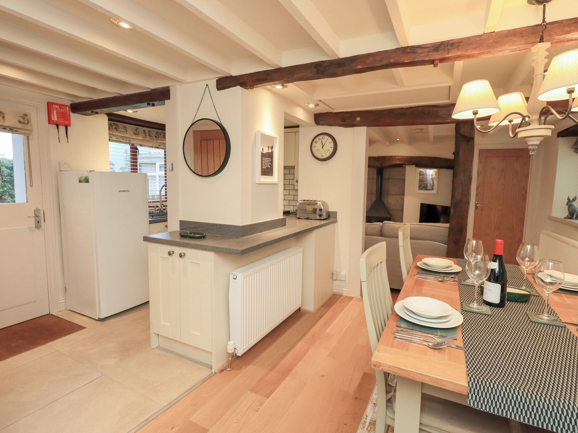 A kitchen with a built-in refrigerator, a round mirror, a clock, and a dining area with a table set for two.