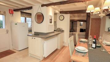 A kitchen with a built-in refrigerator, a round mirror, a clock, and a dining area with a table set for two.