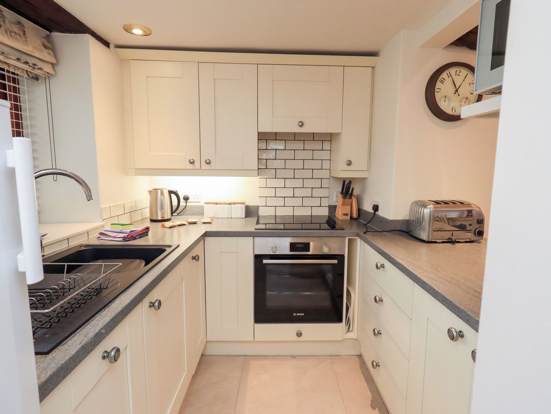 A compact kitchen with white cabinets, a Bosch oven, a toaster, and a kettle.