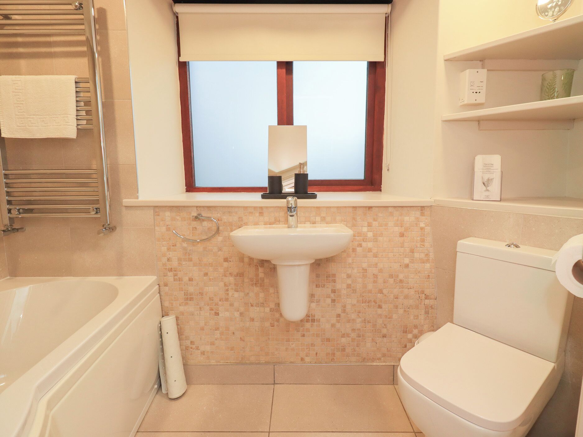 A bathroom with a white sink, a toilet, a bathtub, and a window with a view.