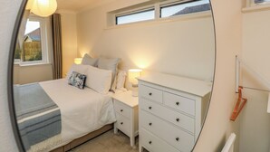 A bedroom with a bed, nightstands, a dresser, a window, and a lamp. - Seafarer's Rest (Chichester)