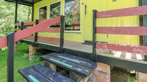 Un bâtiment jaune avec un escalier en bois et un banc.