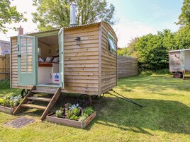 Una casa móvil de madera con puerta verde, un pequeño porche y una ventana.