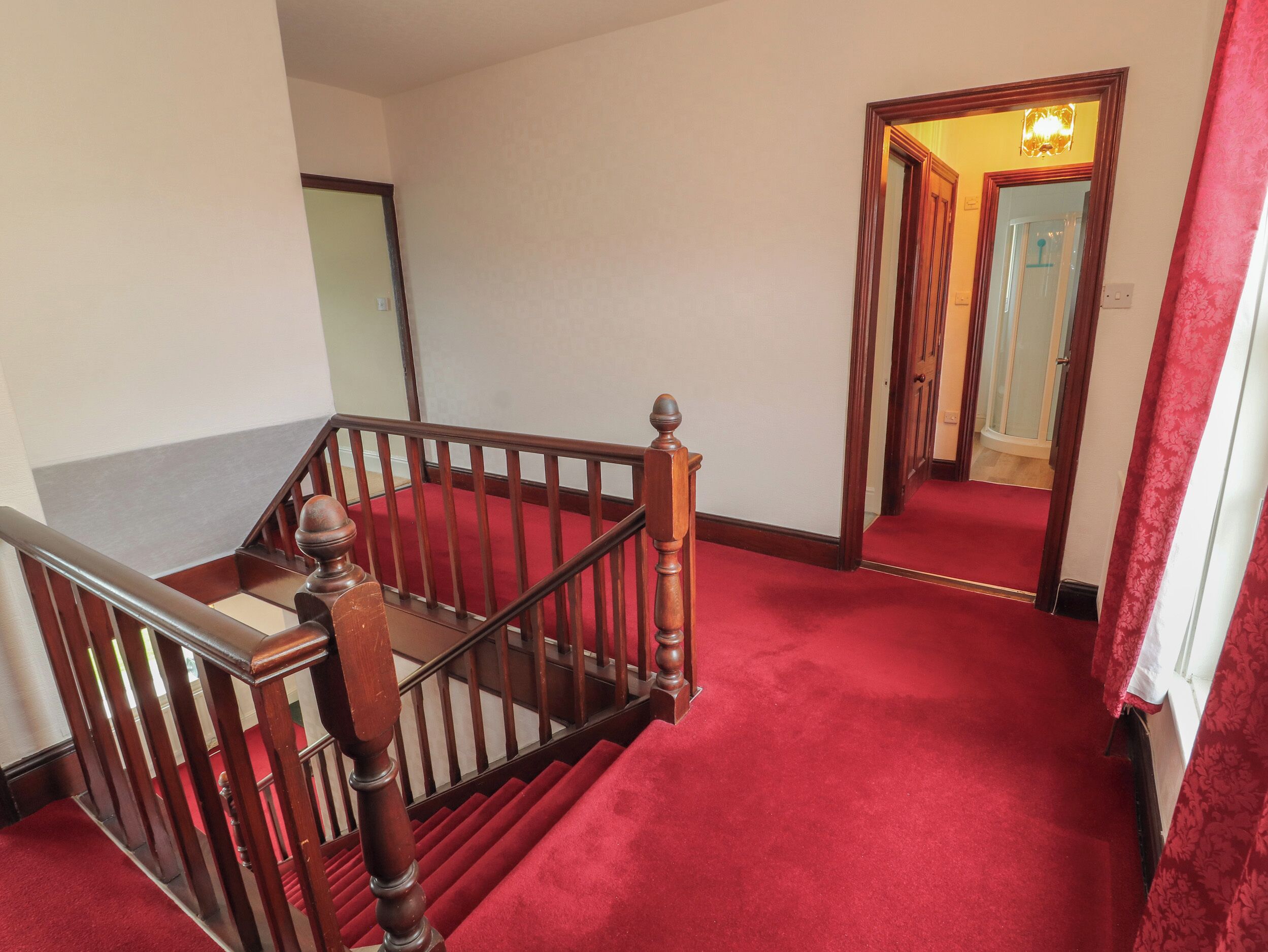 Een trap met een rode loper die leidt naar een kamer met een spiegel en een deur.