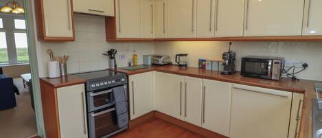A modern kitchen with wooden cabinets, a built-in oven, a microwave, and a coffee maker.