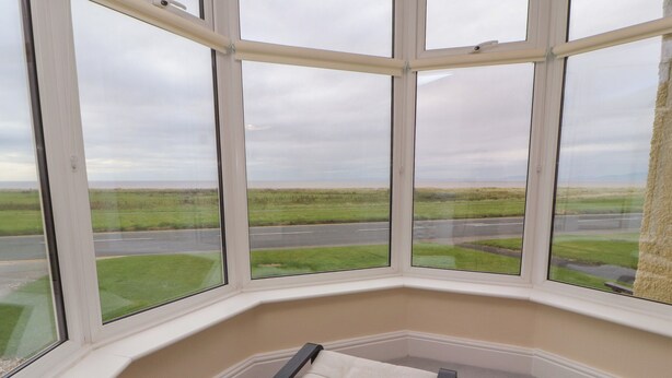 A corner room with a large bay window overlooking a road and fields. - Burnbank (Maryport)