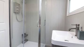A modern bathroom with a glass-enclosed shower, a white sink, and a dark wood vanity.