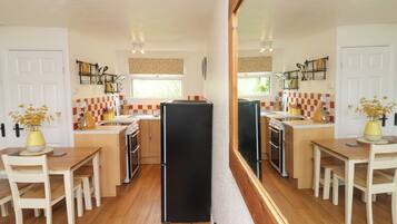 A compact kitchen with wooden cabinets, a black refrigerator, and a window providing natural light.