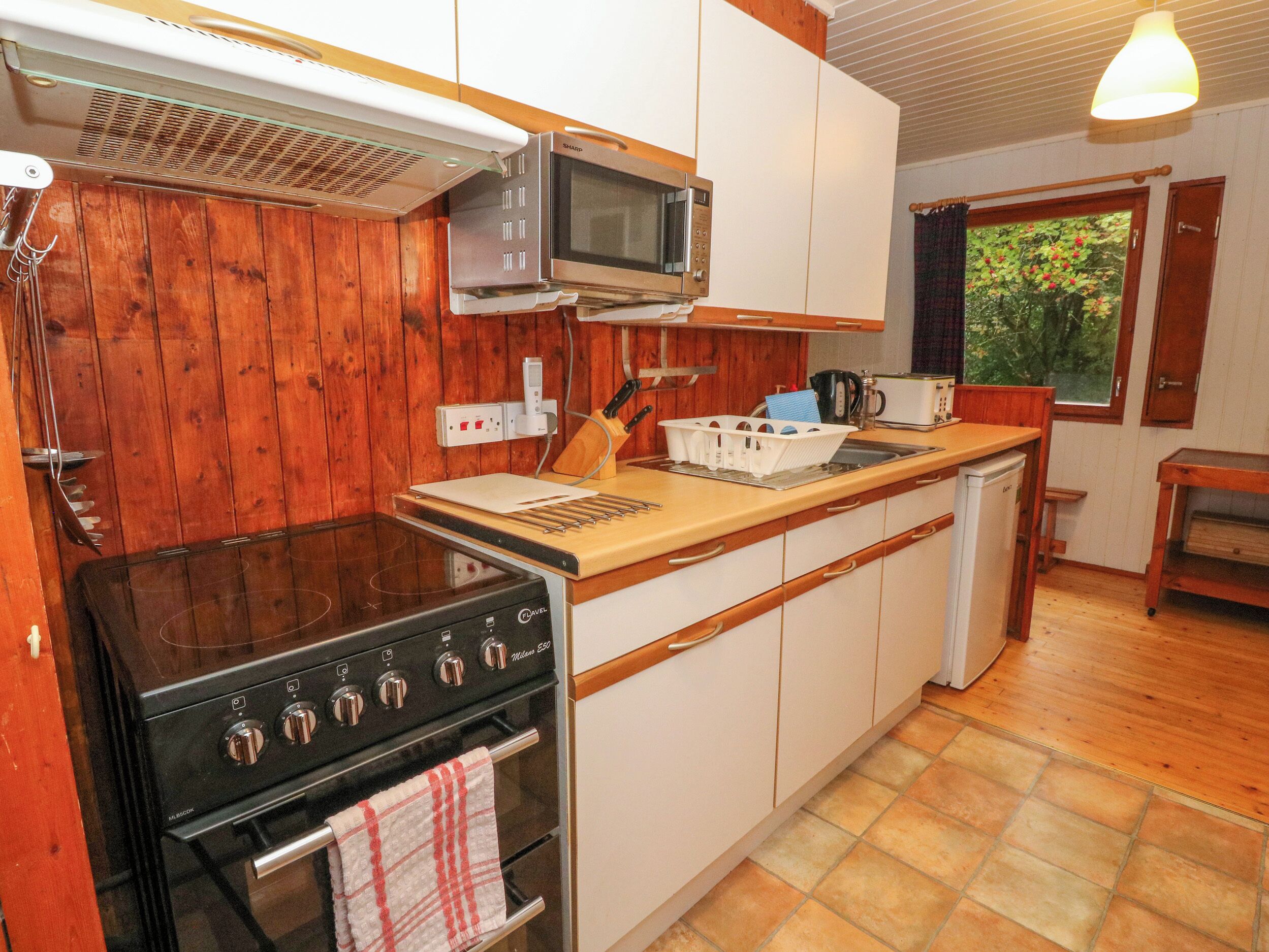 A compact kitchen with a stove, microwave, and a small island with a kettle.